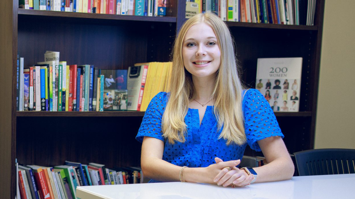 Emily Adcock posing, in front of a bookcase in an office.