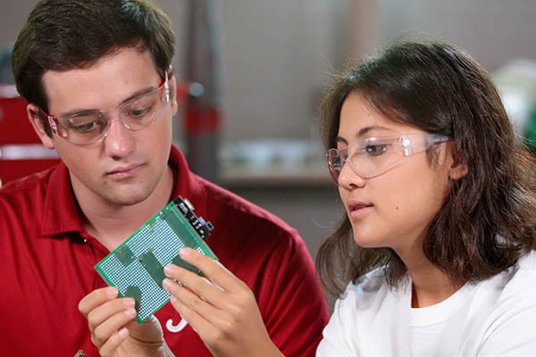 Two students examine a circuit board