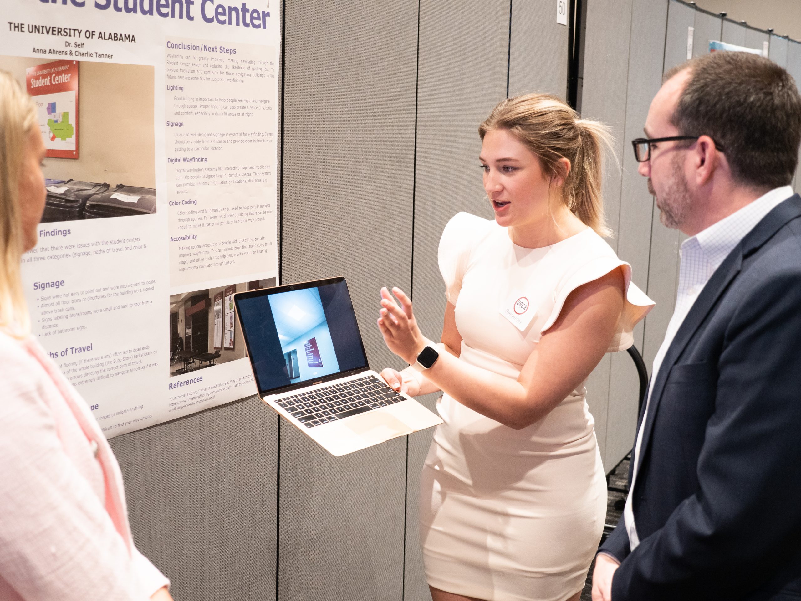 Student with laptop explains her research to the dean