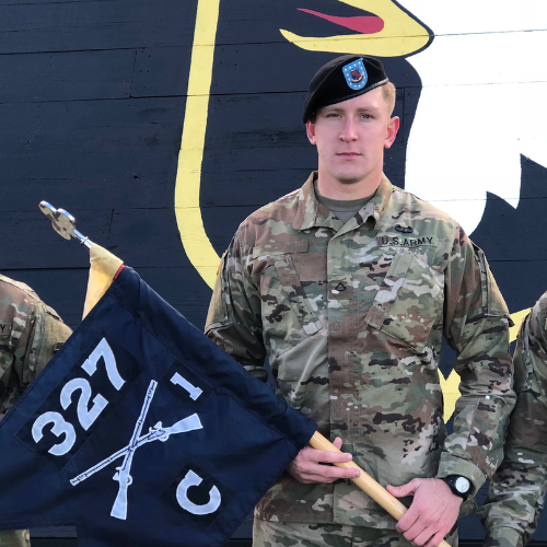 wade burchett standing and holding a battalion flag