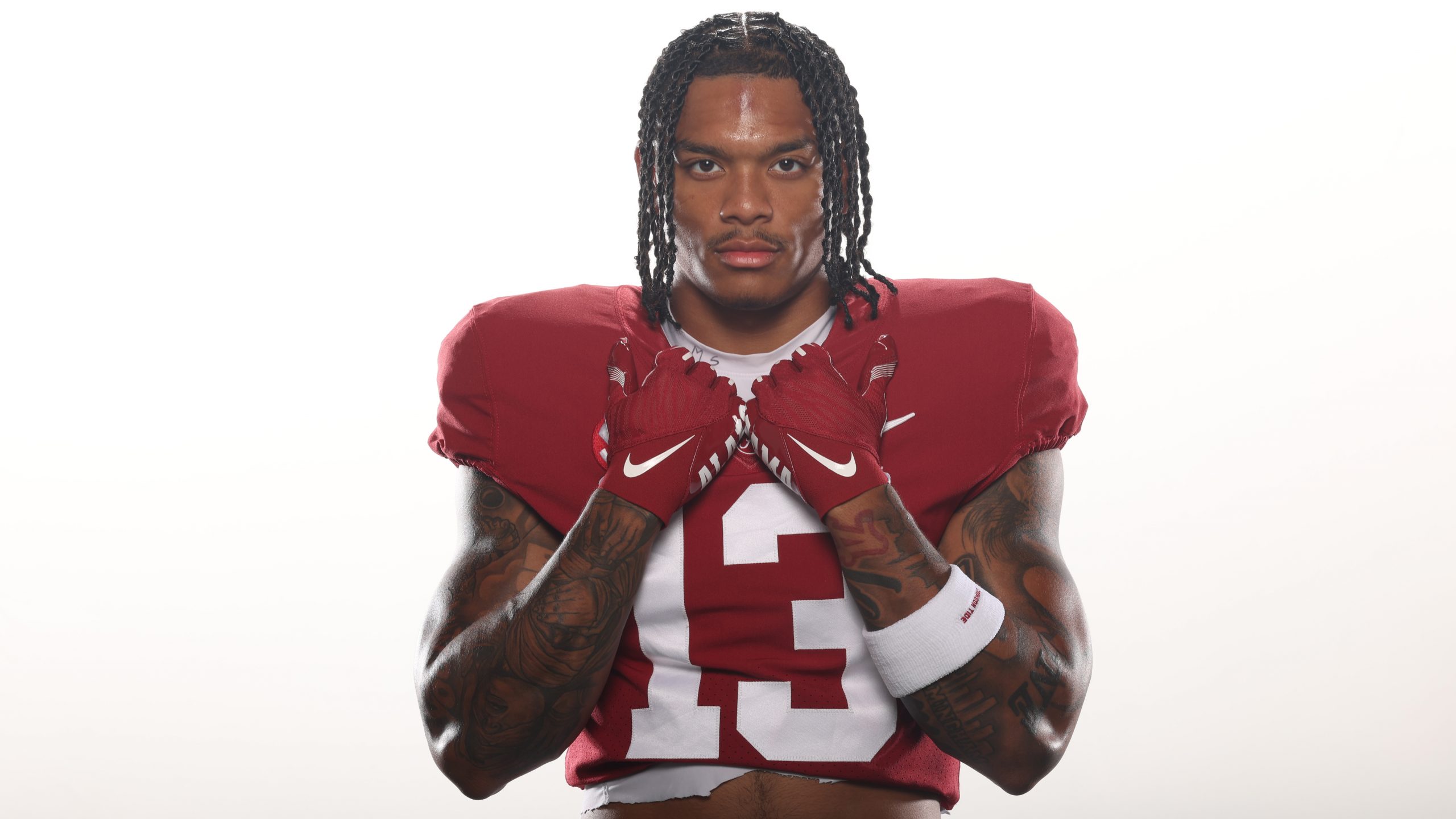 A black male football player poses for a photo in a studio