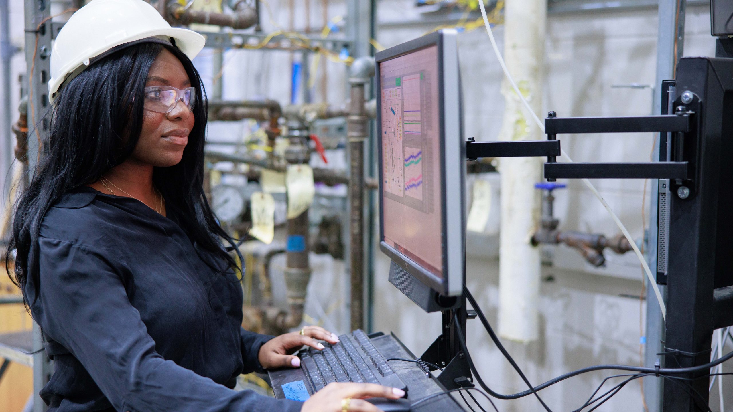 A black woman works at a computer in an engineering lab
