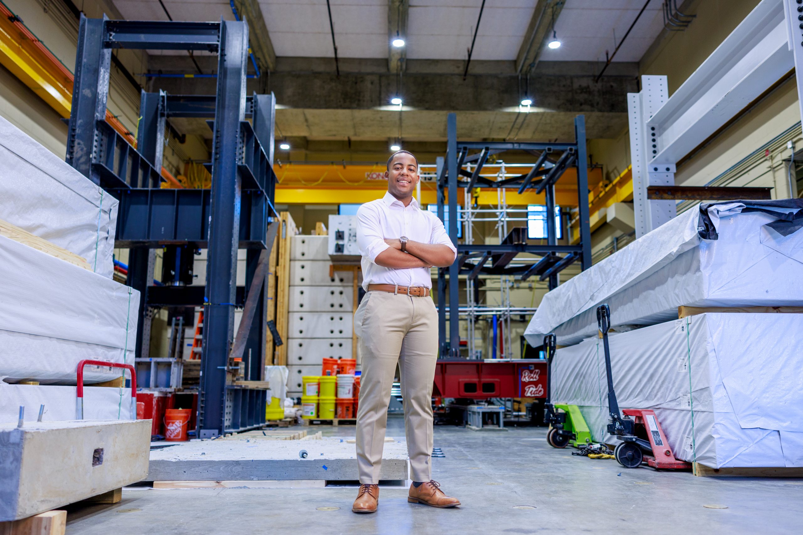 A black male college student poses for a photo in an engineering lab
